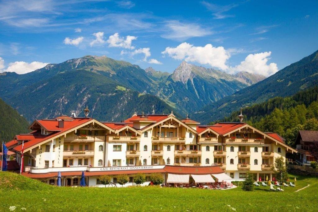 a large hotel with mountains in the background at Vital Sporthotel Kristall in Finkenberg