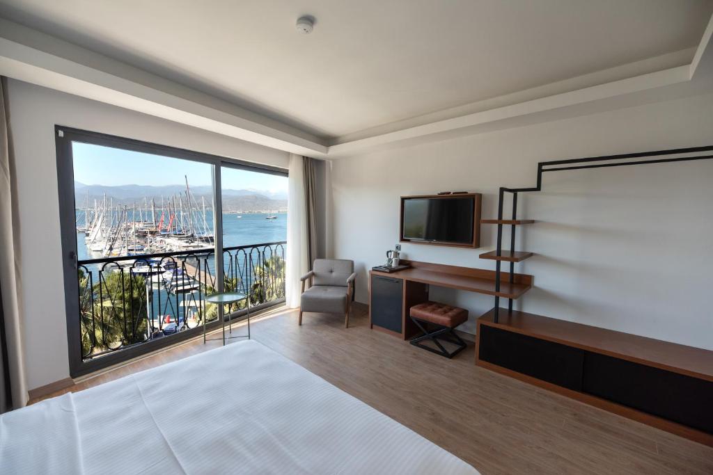 Schlafzimmer mit einem Bett, einem Schreibtisch und einem großen Fenster in der Unterkunft La Farine Hotel in Fethiye