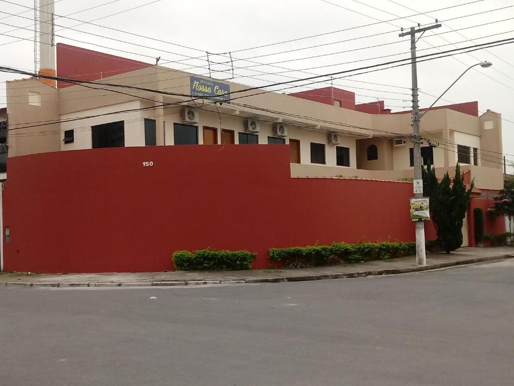 een rood-wit gebouw met een rode muur bij Pousada Nossa Casa in Aparecida