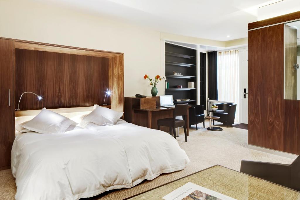 a bedroom with a large white bed and a desk at Hotel du Commerce in Basel