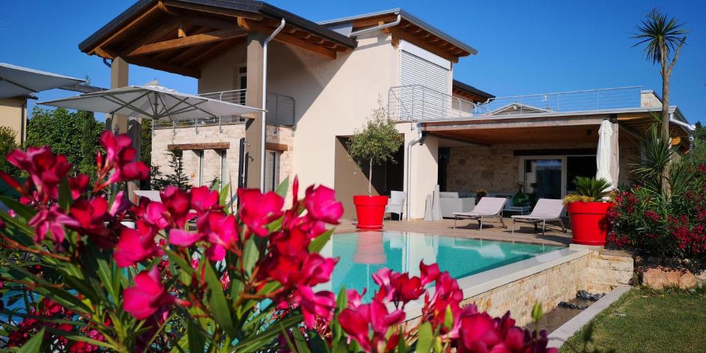 una casa con piscina e fiori rosa di B&B Villa Pelèr a Lazise