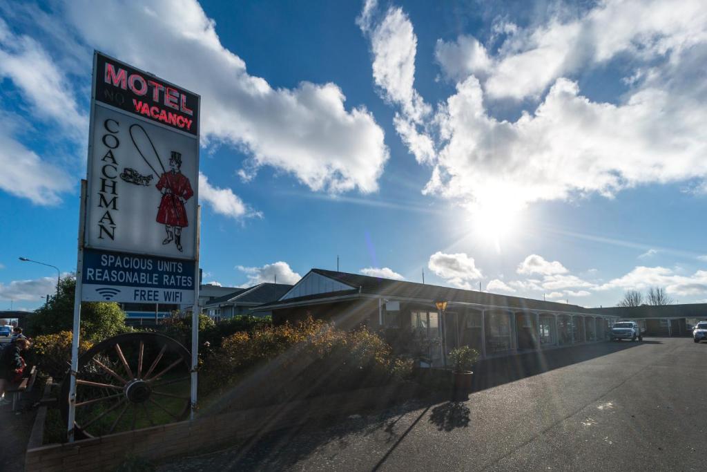 Una señal para un motel con el sol en el cielo en Coachman Motel, en Christchurch