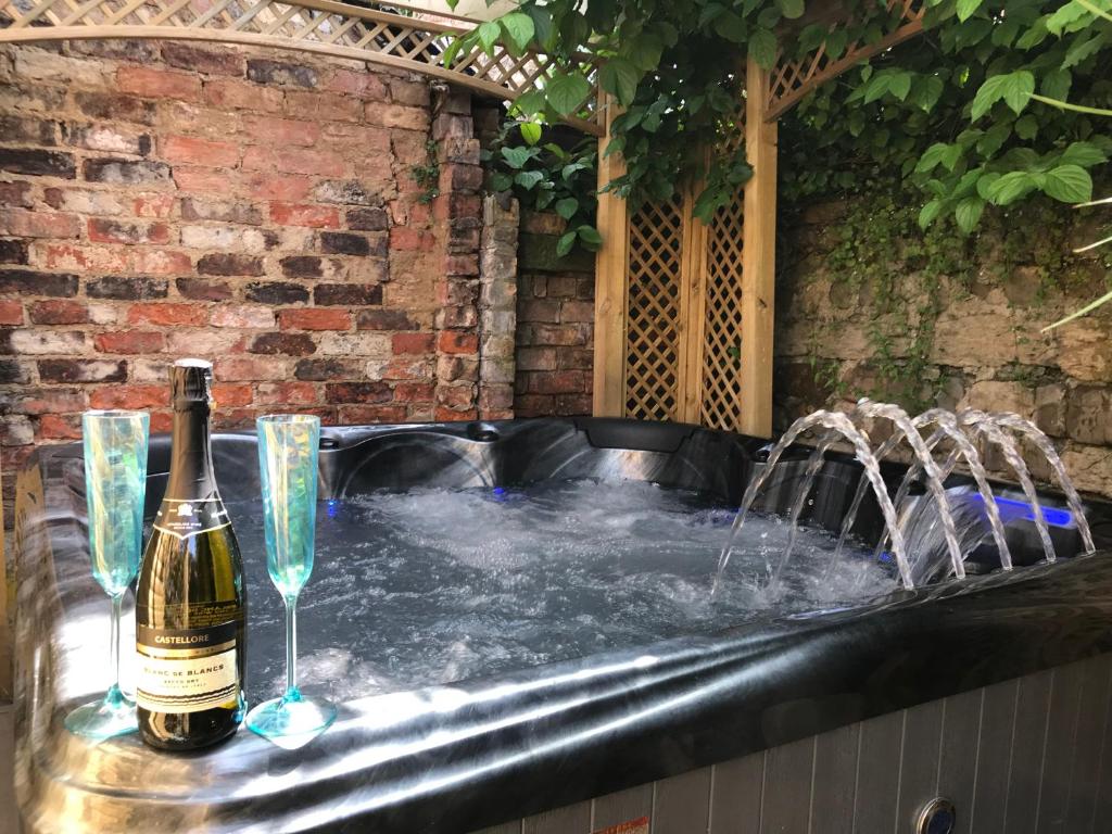 - Uma garrafa de champanhe e 2 copos numa banheira de hidromassagem; em Marwood Cottage em Ripon