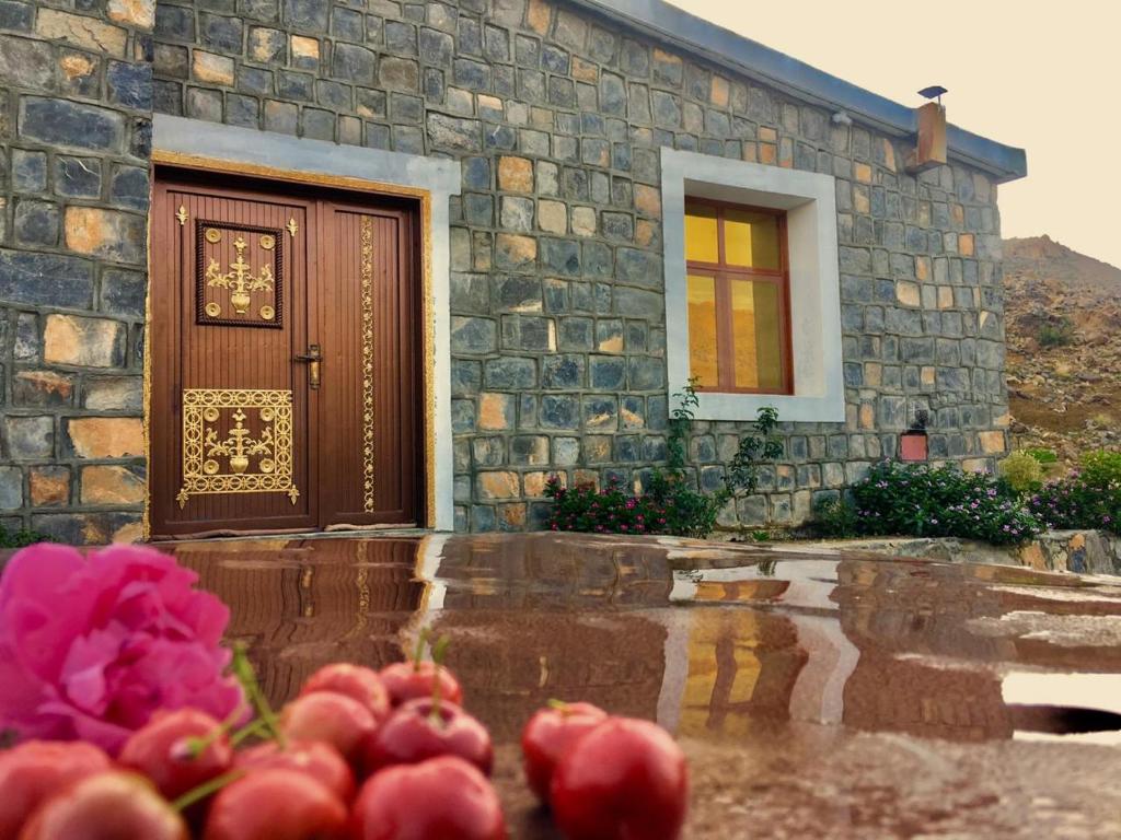 a house with a door and pink flowers in front of it at Jabal Shams Villa in Sa‘ab Banī Khamīs