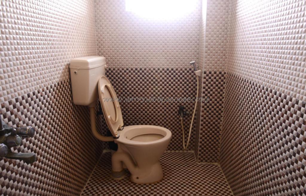 a small bathroom with a toilet in a stall at Green Grande Inn in Chennai