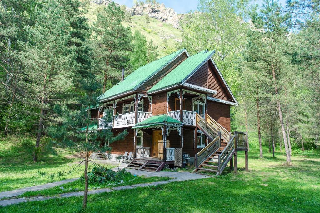 a log cabin in the woods with a green roof at Touristic complex Taiezhnik in Manzherok