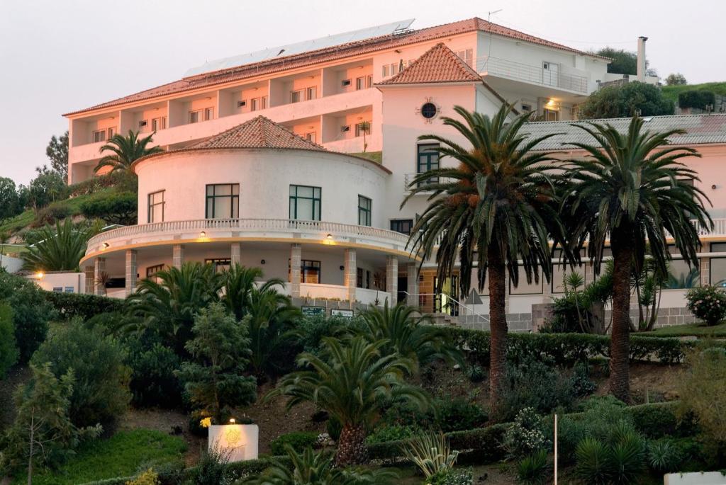 a large building on top of a hill with palm trees at INATEL Foz Do Arelho in Foz do Arelho