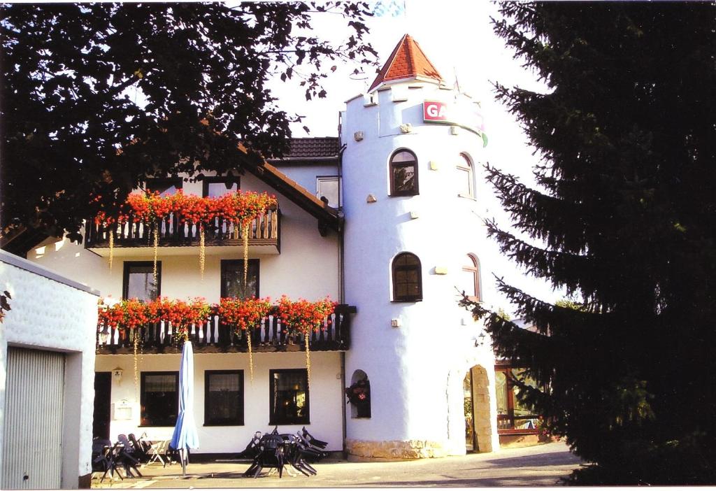 biały budynek z skrzyniami kwiatowymi i balkonem w obiekcie Hotel Gasthof Turm w mieście Grünhaid