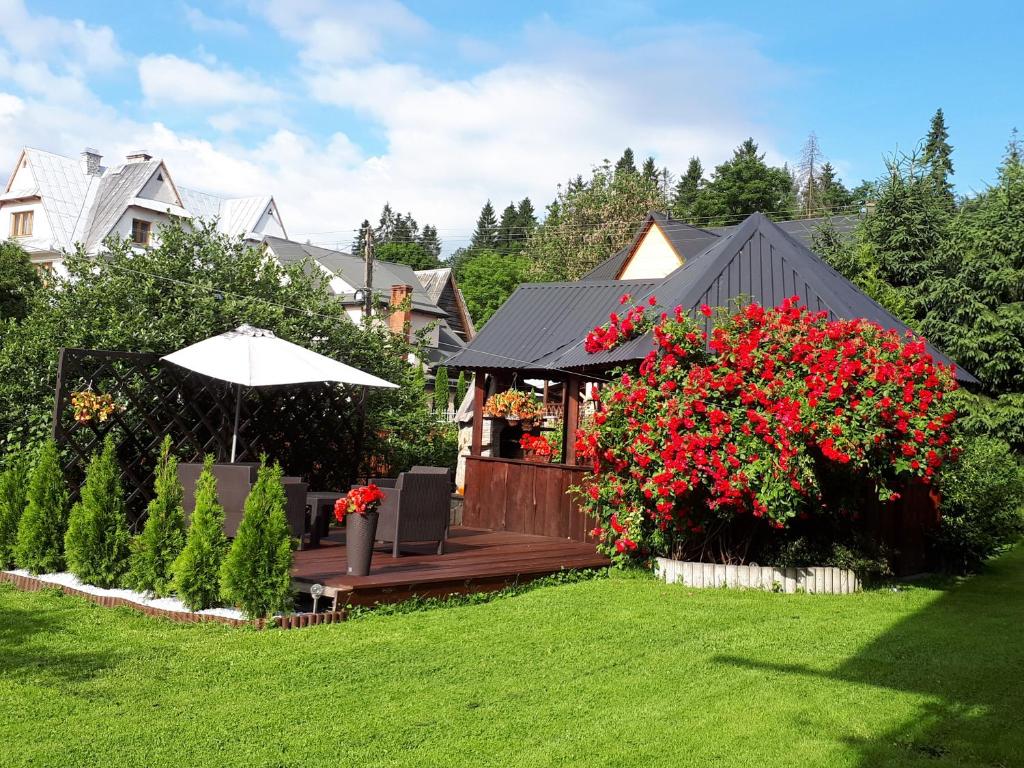 a garden with a wooden deck with red flowers at Apartament Glamour in Biały Dunajec