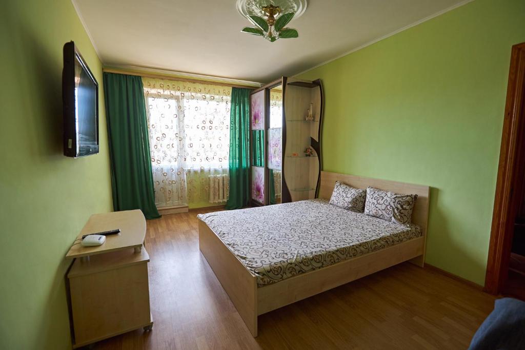 a bedroom with a bed and a television in it at Babylon Apartments On Kievskaya Street in Rivne