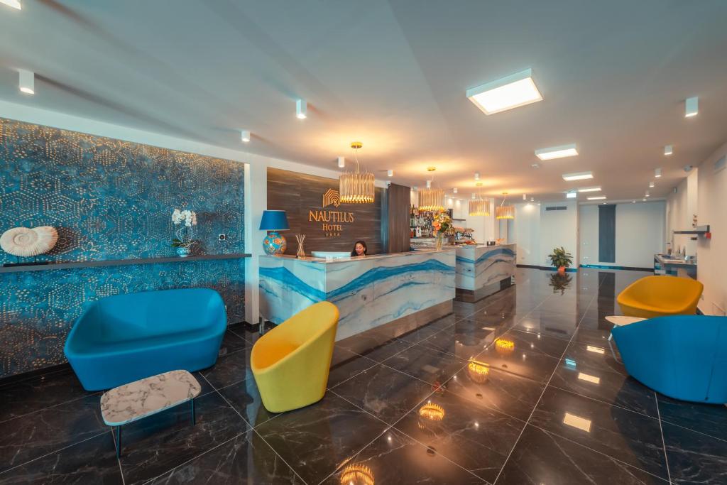a lobby with a waiting area with blue and yellow chairs at Nautilus Hotel in Giardini Naxos