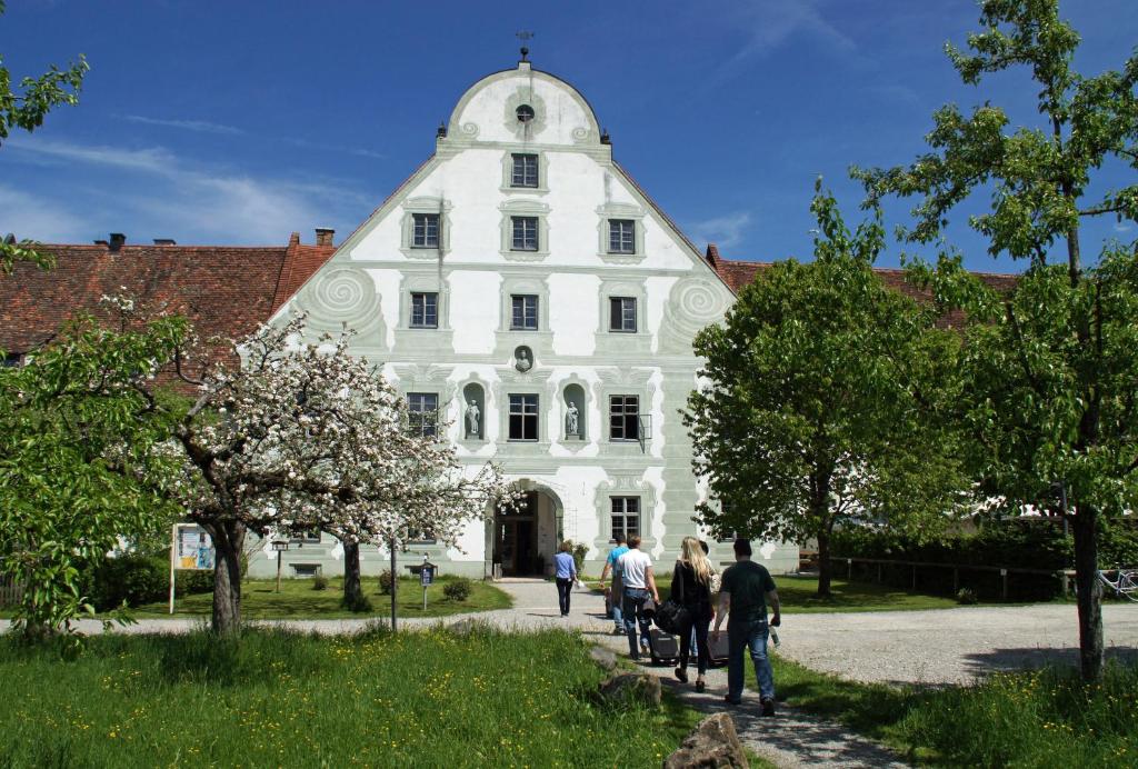 un gruppo di persone che si trovano di fronte a un edificio bianco di Zentrum für Umwelt und Kultur - Gästehaus und Jugendbildungseinrichtung im Maierhof a Benediktbeuern