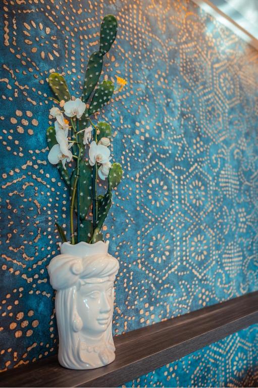 a white vase with flowers in it next to a wall at Nautilus Hotel in Giardini Naxos