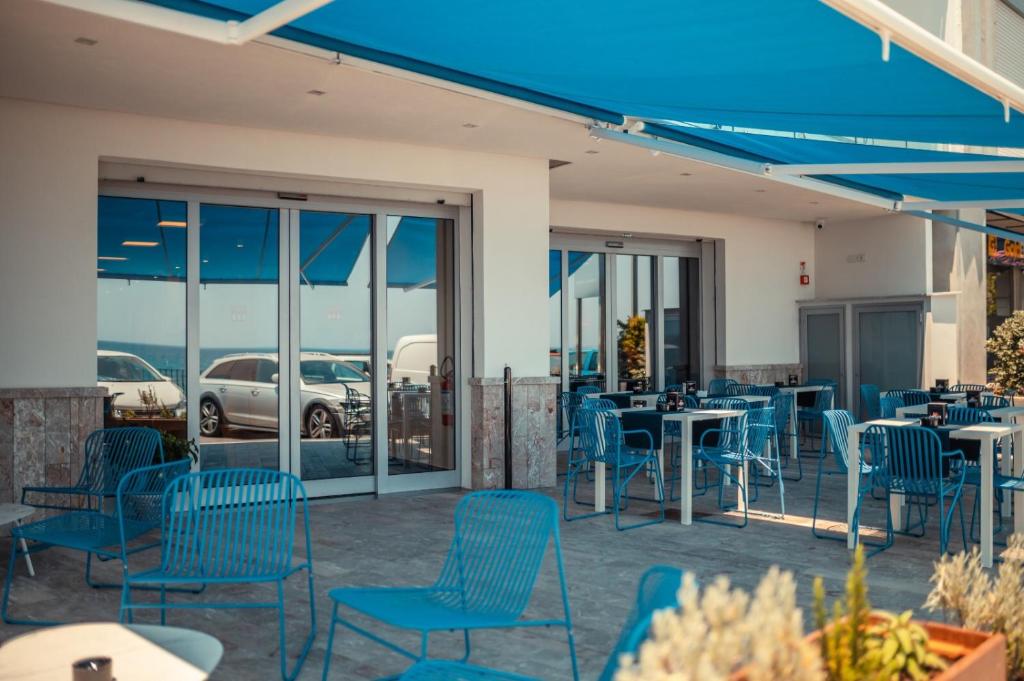 a patio with blue chairs and tables and windows at Nautilus Hotel in Giardini Naxos
