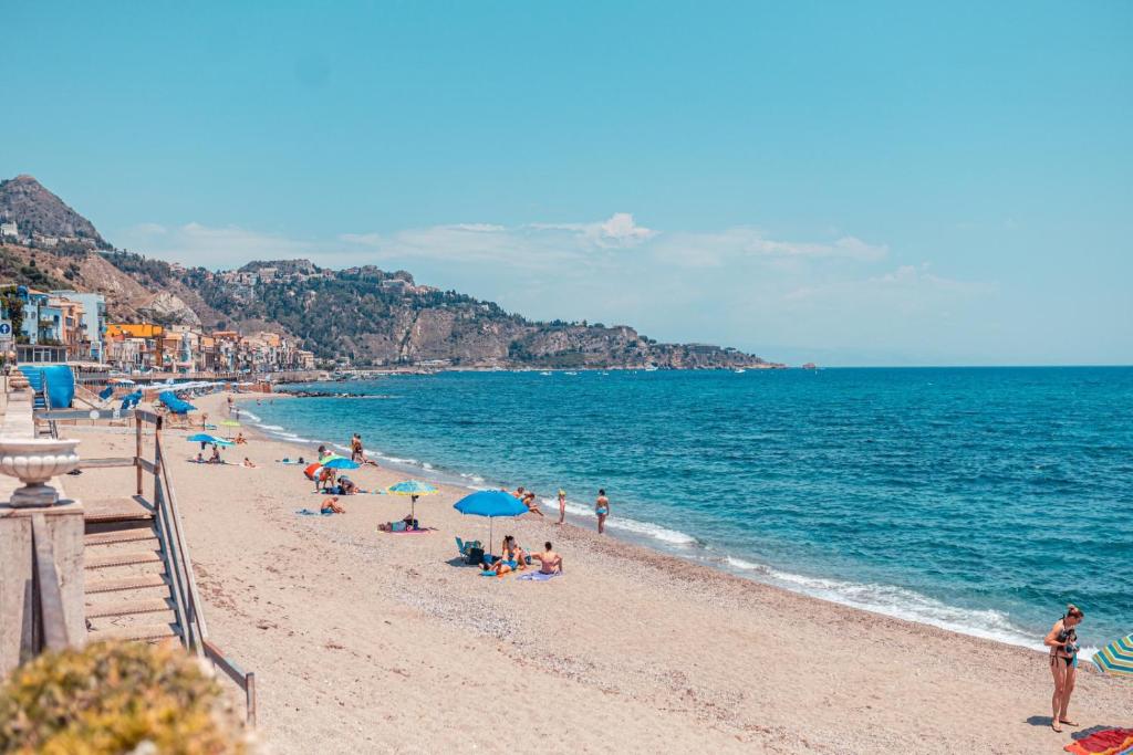 a group of people on a beach near the water at Nautilus Hotel in Giardini Naxos