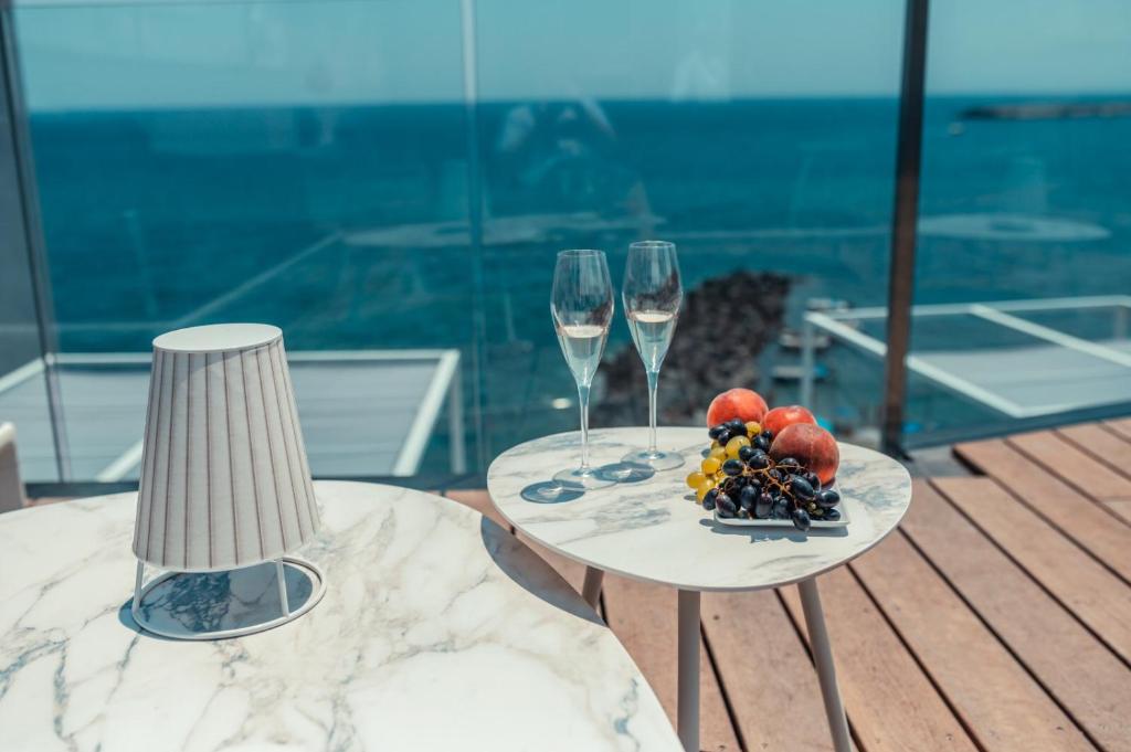 a table with two glasses of wine and a plate of fruit at Nautilus Hotel in Giardini Naxos