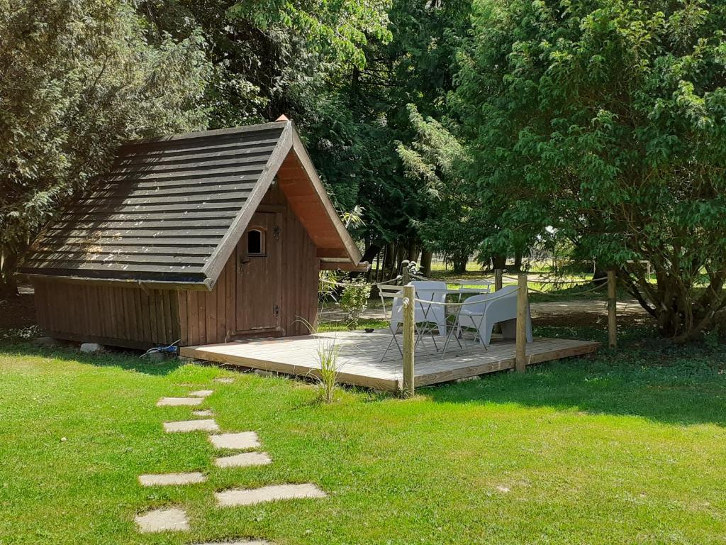 eine Holzhütte mit einer Terrasse und Stühlen im Gras in der Unterkunft Cabane Aligoté in Saint-Albain