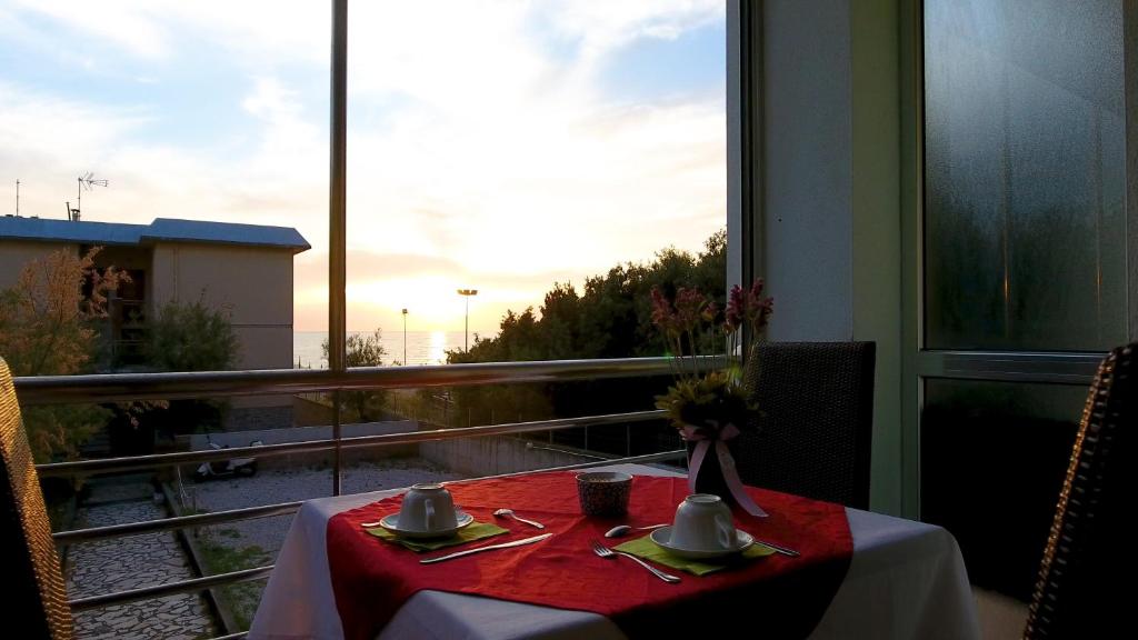 a table with a red table cloth and a view from a window at Hotel Aurora in San Vincenzo