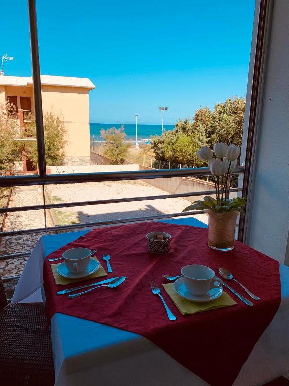 a table with a red table cloth with two cups and a tableknife at Hotel Aurora in San Vincenzo