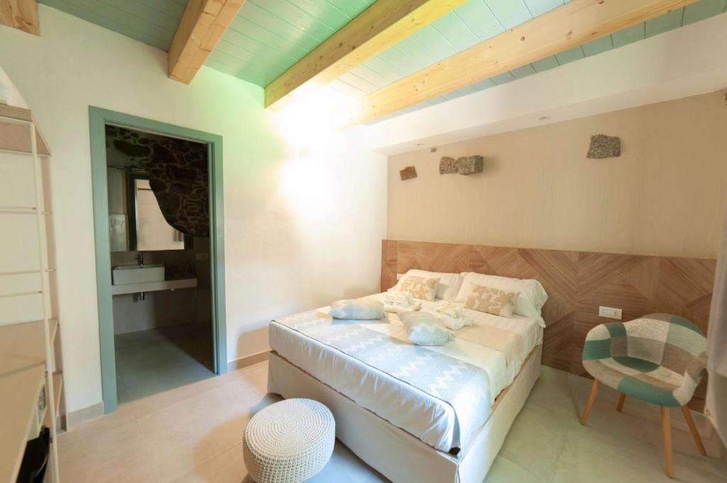 een slaapkamer met een bed en een stoel bij PERDAS ROOMS in Villasimius