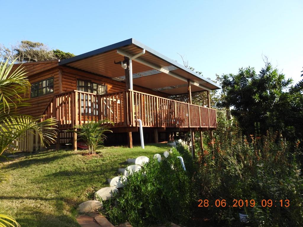 a large wooden house with a porch and a yard at Illovo Beach Inn in Amanzimtoti