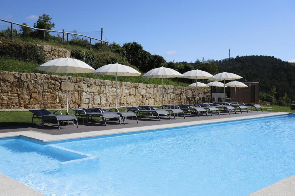 - une rangée de chaises et de parasols à côté de la piscine dans l'établissement Ternaldo Agroturismo & Relax, à Arco de Baúlhe