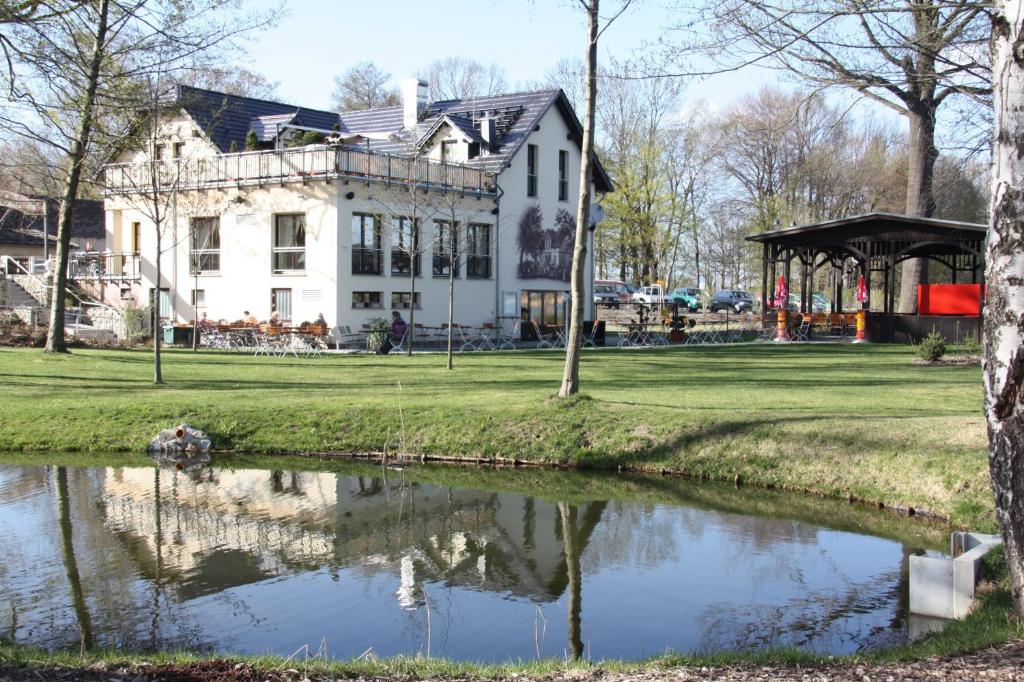 uma grande casa branca com um lago em frente em Pension-Maustmühle em Peitz