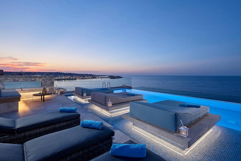 a swimming pool with couches and a view of the ocean at Seafront Apartments by Myseasight in Hersonissos