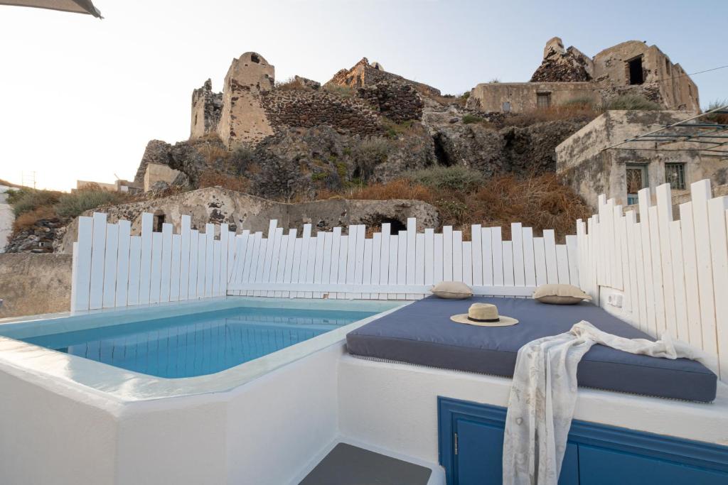 a pool with a bed and a castle in the background at Santo Castello in Akrotiri