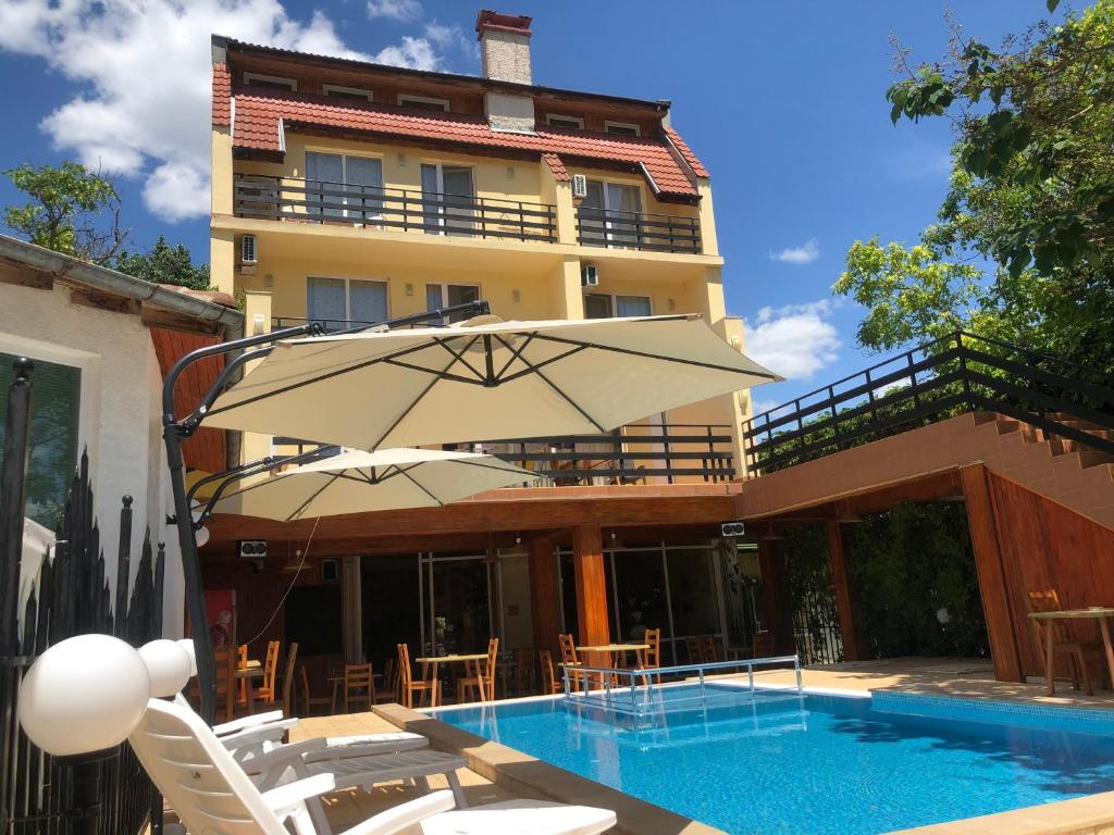 a pool with chairs and an umbrella next to a building at Family Hotel Central in Kranevo