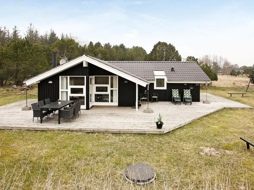 a black house with a deck with a picnic table at 5 person holiday home in lb k in Ålbæk
