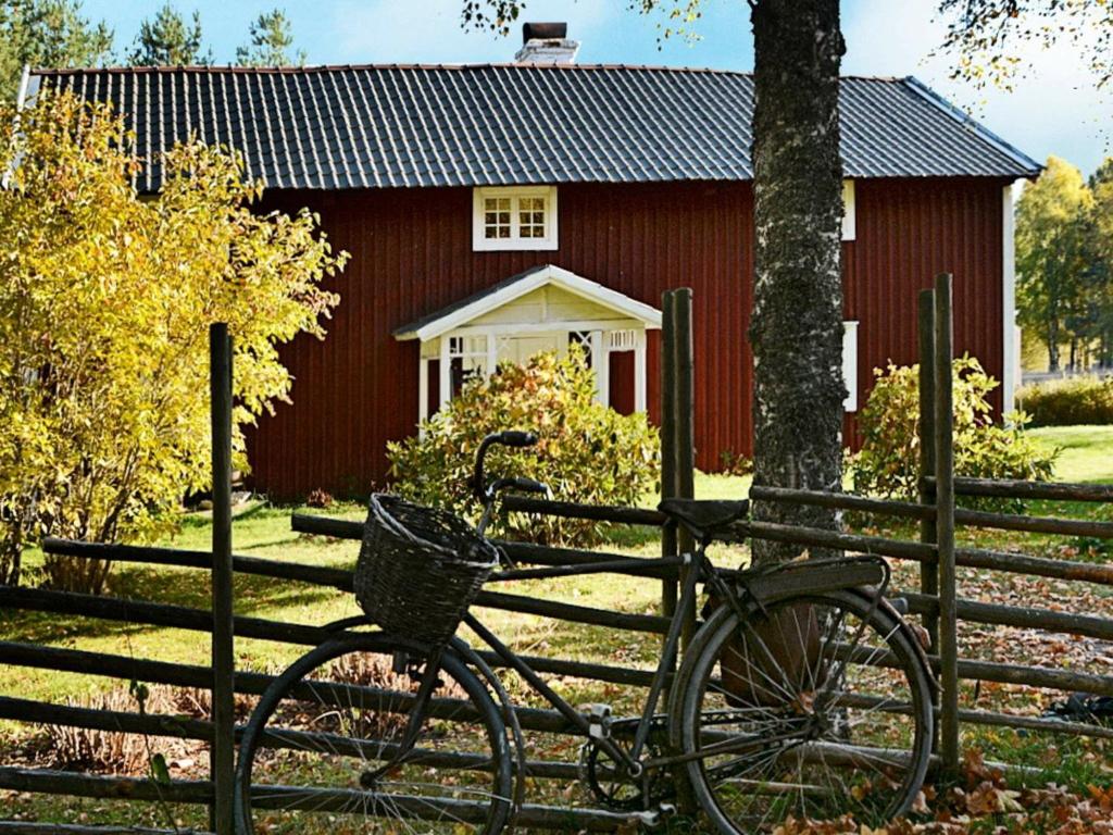 uma bicicleta estacionada ao lado de uma cerca em frente a um celeiro vermelho em Three-Bedroom Holiday home in Jönköping em Norrahammar