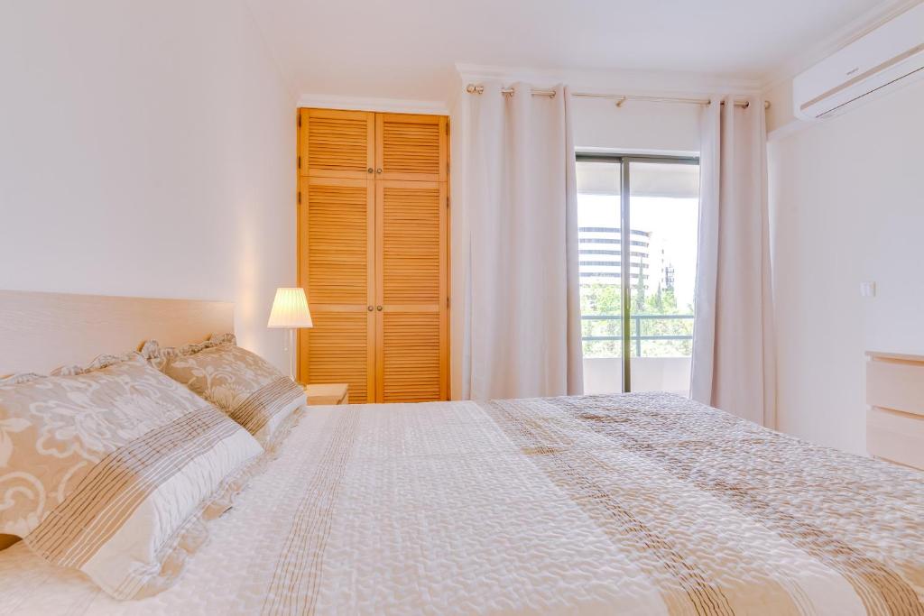 een witte slaapkamer met een bed en een raam bij Tália I - City Center - Vilamoura in Vilamoura