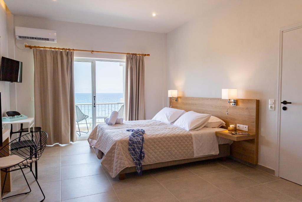 a bedroom with a bed with a view of the ocean at Euphoria Blue studio apartments in Artemida