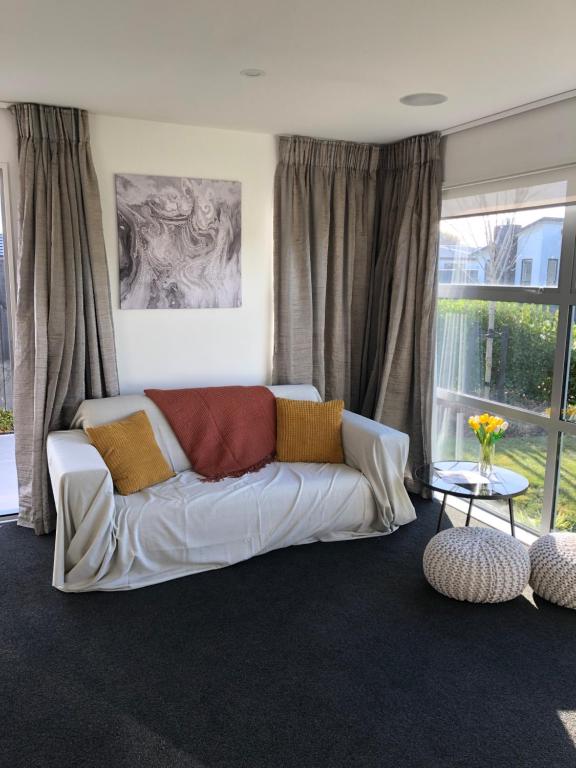 een woonkamer met een witte bank voor een raam bij 7*7 holiday home in Christchurch