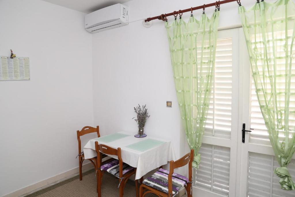 ein Esszimmer mit einem Tisch, Stühlen und einem Fenster in der Unterkunft Apartman Sardelić in Korčula