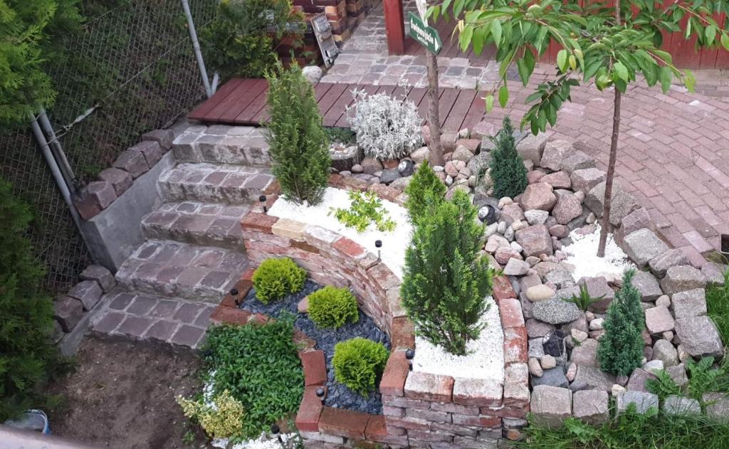 a garden with a brick pathway with plants and rocks at Pokoje u Michała in Międzyzdroje