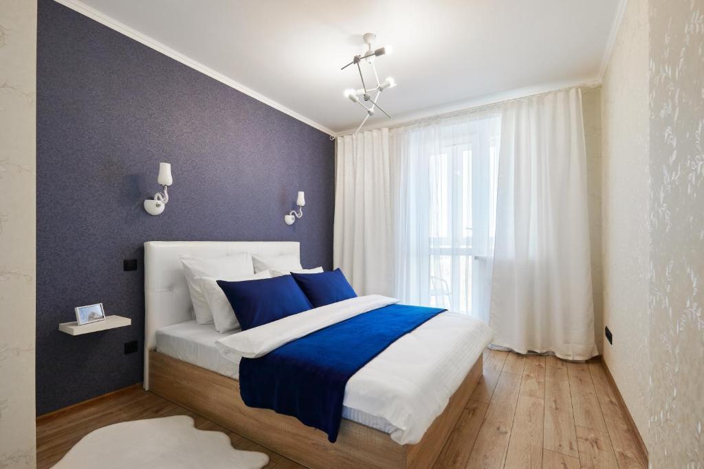 Un dormitorio con una cama azul y blanca y una ventana en PaulMarie Apartments on Mayakovskogo 35, en Minsk