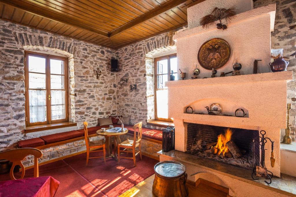 a living room with a fireplace and a table and chairs at Archontiko Montana in Vyzitsa