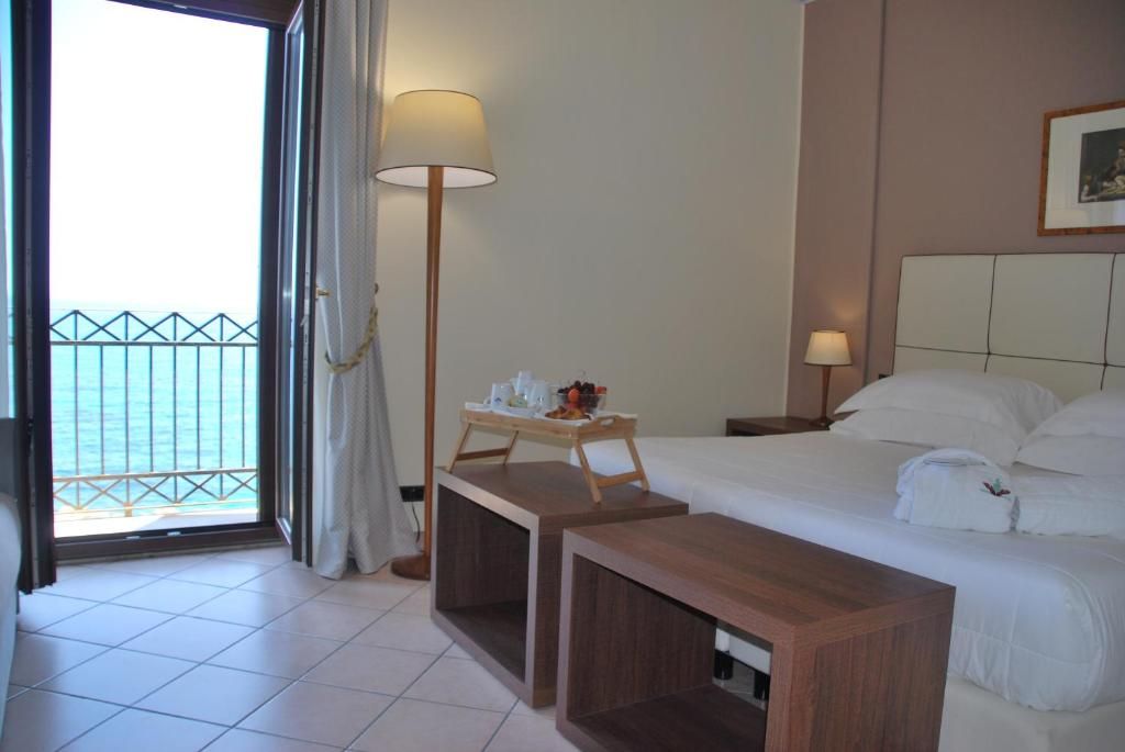 ein Hotelzimmer mit einem Bett und einem großen Fenster in der Unterkunft Domus Mariae Albergo in Syrakus