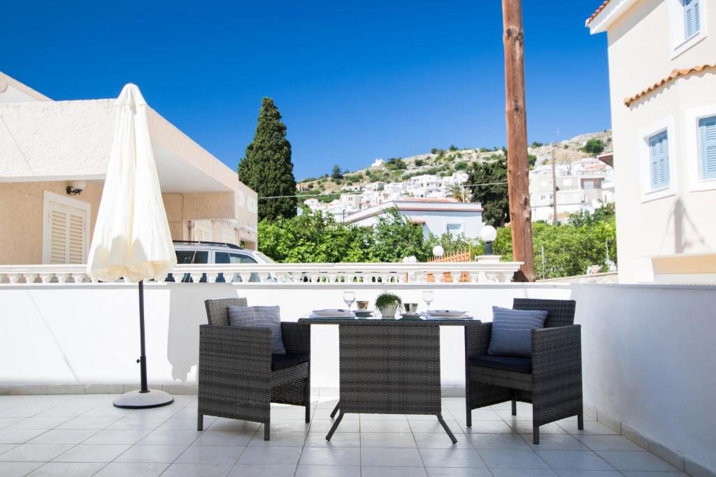 un patio con una mesa con sillas y una sombrilla en Villa Maria, en Voládha