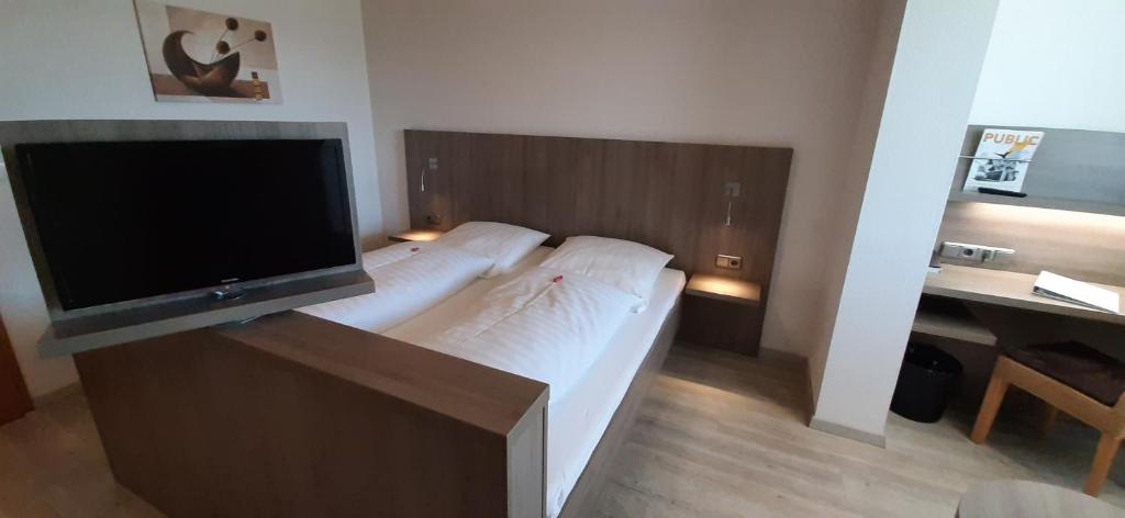 a bedroom with a bed with a flat screen tv at Landgasthof Zur scharfen Ecke in Hildesheim