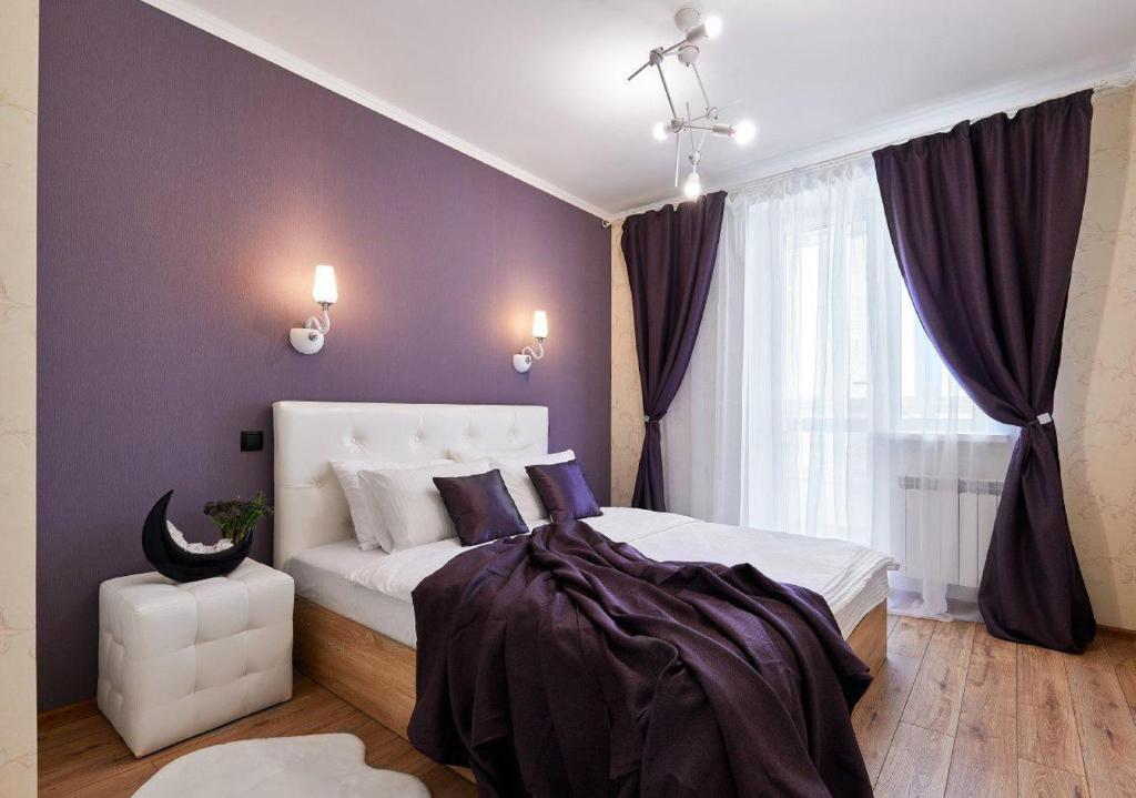 Un dormitorio con una cama blanca con paredes moradas y una ventana en PaulMarie Apartments on Mayakovskogo, en Minsk