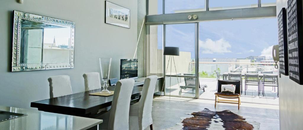 City Fringe Apartment with Sky Tower and City Views في أوكلاند: غرفة طعام مع طاولة وكراسي ومدفأة
