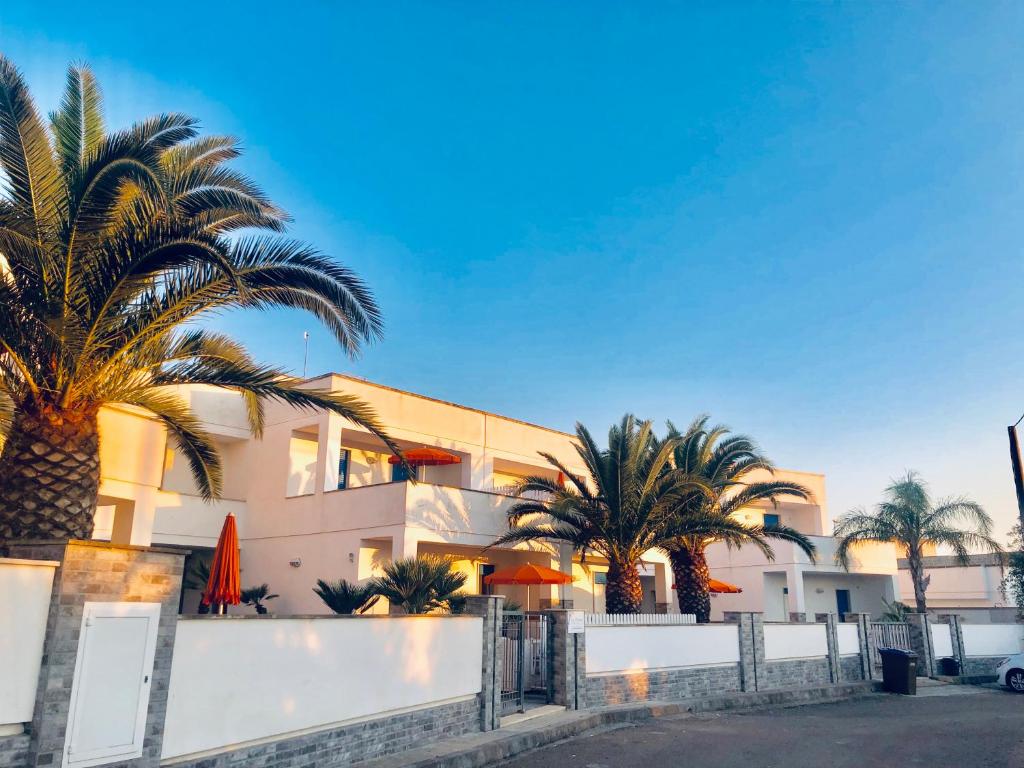 a building with palm trees in front of it at Residence Le Palme in Marina di Mancaversa