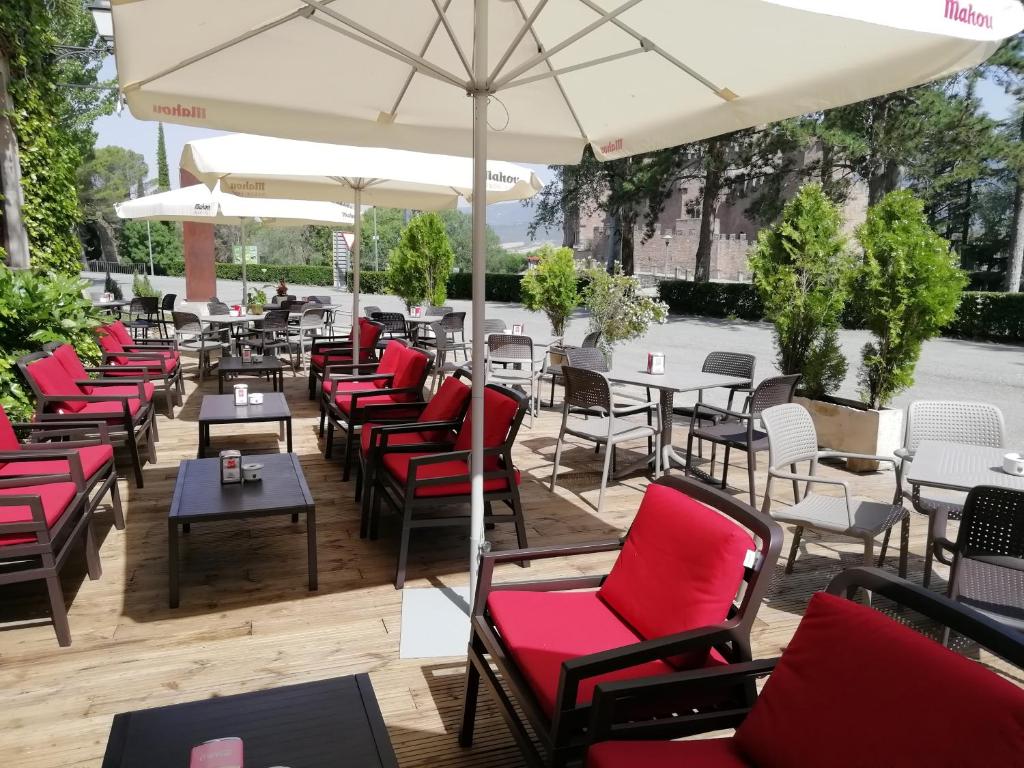 a patio with red chairs and tables and an umbrella at Hotel Xabier in Javier