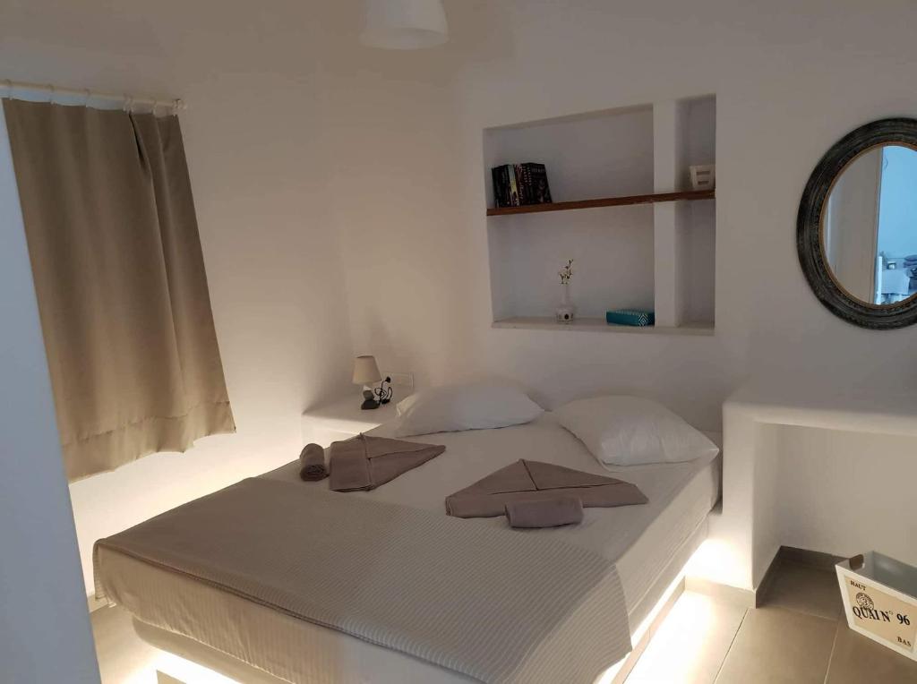 um quarto branco com uma cama grande e um espelho em SAND & WAVES HOUSE em Andiparos