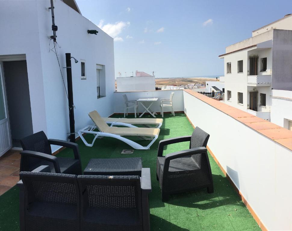 a balcony with chairs and a table on a building at Arco - Virgen Apartamentos y Habitación in Conil de la Frontera