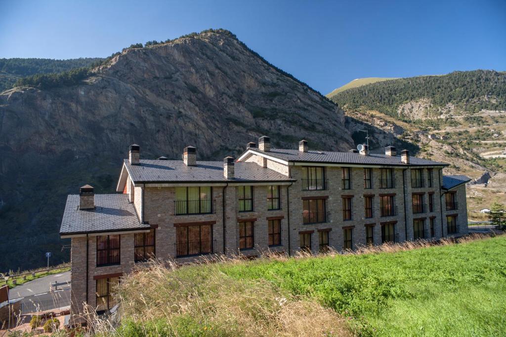 un edificio en la cima de una colina con una montaña en Obaga Blanca & Spa, en Canillo