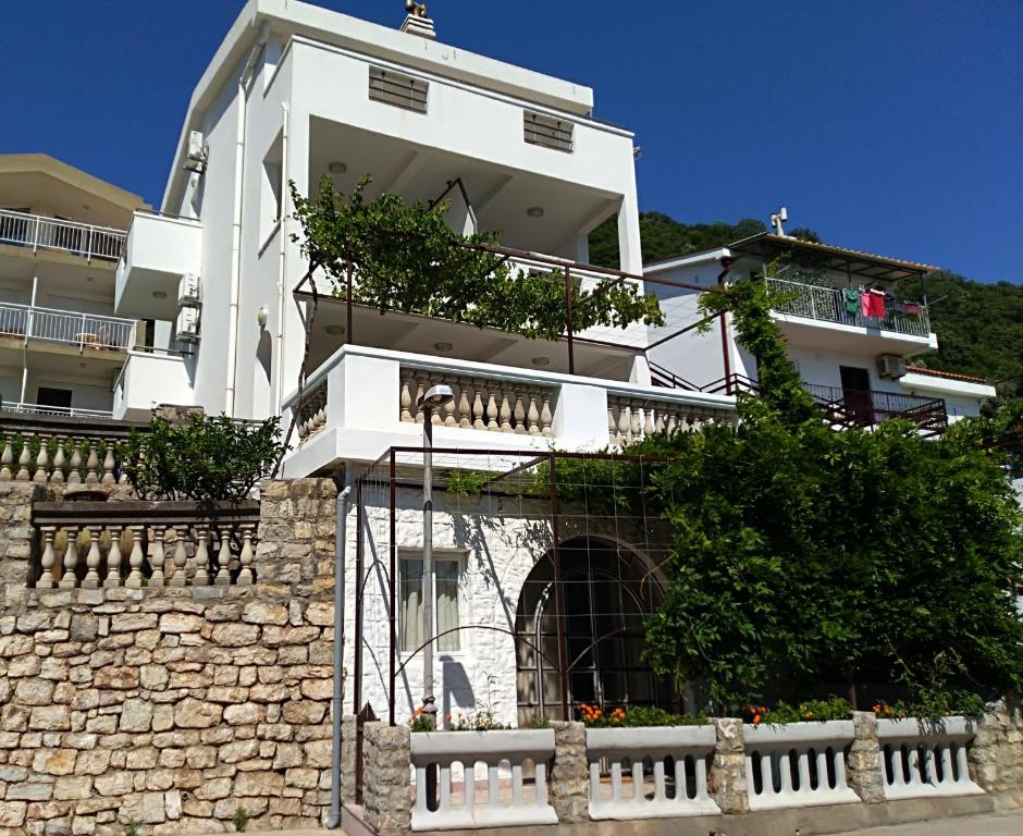 a large white building with a stone wall at Apartmani Jovanovic in Petrovac na Moru